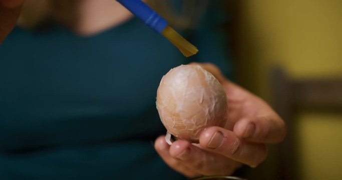 Young woman decorating easter egg with white paper