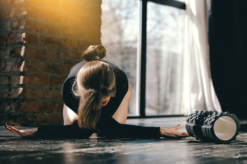A girl with ponytail hair and a black training suit is doing stretching exercises for the joints of...