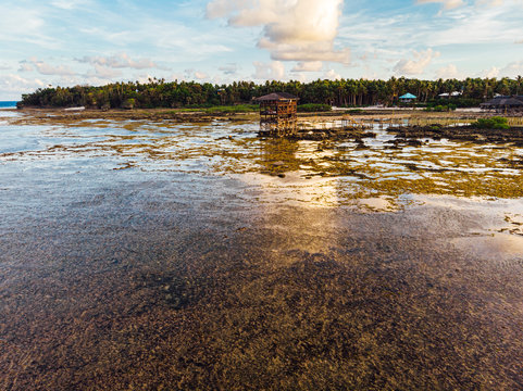 Aerial view of magestic landscape at sunset in the reef of Cloud9 at low tide with coral reef and transparent waters, Siargao Island, Philippines