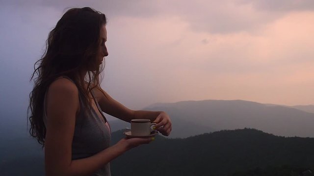 beautiful girl enjoy the organic fresh coffee or masala chai in india hills with top nice view at evening sunset