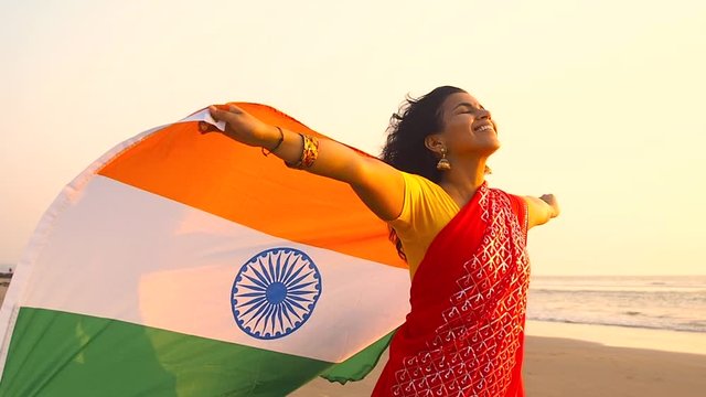 patriotism, independence day August 15 and holidays concept.happy smiling young woman with national indian flag on summer beach