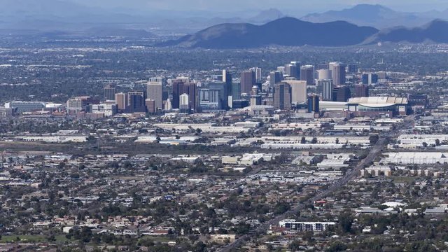 Phoenix, Arizona - March 14 2020: A long-lens timelapse looking down towards downtown Phoenix as clouds cast their shadow on the ground and cars move along highways and roads including I17.