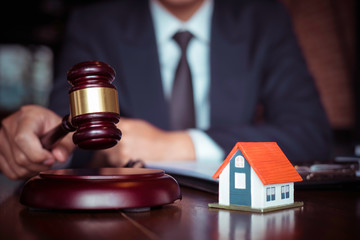 Real Estate Law concept. Gavel on sounding block in hand's Male judge at a courtroom, working for the insurance compensations. report the case on table in modern office.