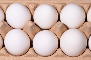 White eggs lie in two rows in paper packaging. The eggs were shot close-up and flat lay. Minimalistic and high-quality photo for your design.