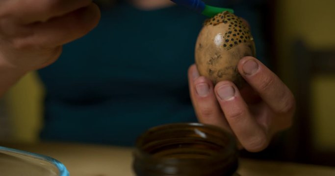 Young woman decorating easter egg with leopard print paper