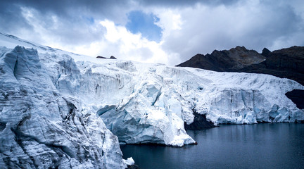 Aerial closeup view of Pastoruri glacier entering the lake. Structure of the ice, cloudy day, mountains in the background.
