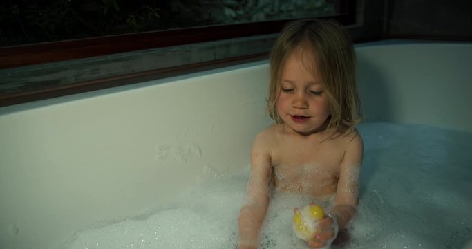 Little boy having a bubble bath with his rubber duck