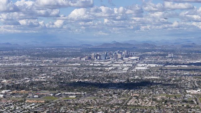 Phoenix, Arizona - March 14 2020: Timelapse looking down towards downtown Phoenix as clouds cast their shadow on the ground, planes take off from Phoenix Sky Harbor International Airport