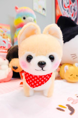 Soft plush toy of cute puppy with red scarf. Pomeranian dog doll. 