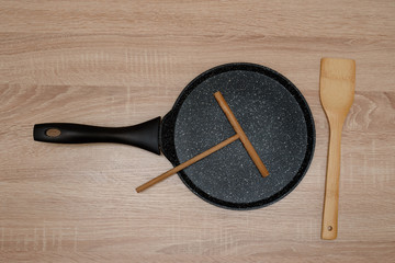 New black iron pan for baking pancakes with timber spatula, spatula, wooden background, table