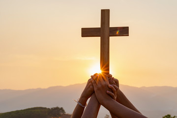 Human hands holding a crucifix symbol with bright sunbeam on the sky. Crucifixion Of Jesus Christ