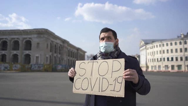  Man in medical mask ask to stop epidemic COVID 19 with poster  on city  street. 