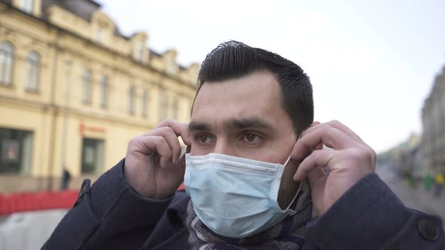 Virus problem team. Сaucasian man puts off medical mask stand on city street. Portrait

