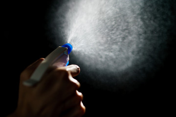 Woman's hands with blue foggy spraying disinfectant to stop spreading  coronavirus or COVID-19.