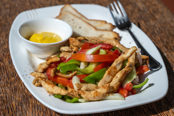 Roasted chicken fillet with vegetables and bread on a white plate, closeup