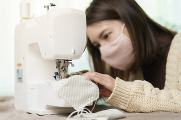 Woman sewing medical masks at home. Sewing on a sewing machine