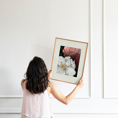 Woman hanging a frame on a white wall