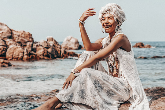 cheerful young stylish woman wearing turban on the beach