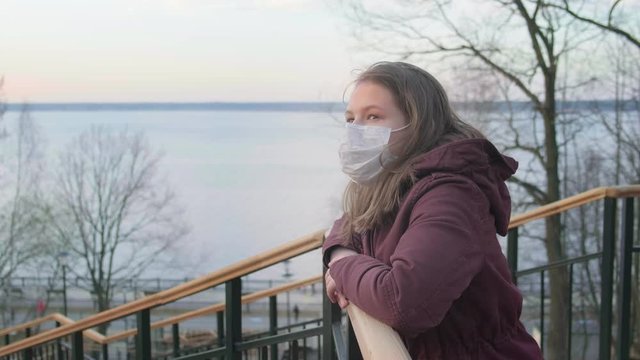 Young girl in black mask alone outdoors. Coronavirus pandemic