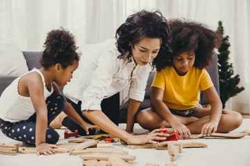 Mother parent playing with children learning to solve puzzle toy at home apartment. Nanny looking or childcare at living room black people.