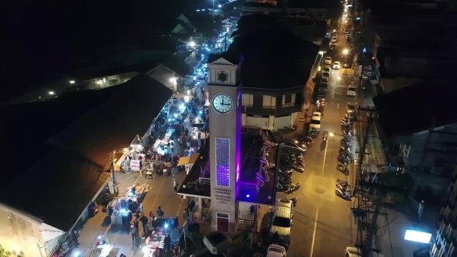 Aerial Footage of The Vietnamese Memorial Clock Tower in Nakhon Phanom Province, Thailand Surrouned by Lively Night Walking Street.