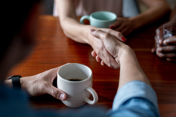 People shaking hands over coffee