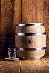 Old oak barrel and glass of high quality distilled alcohol. Brazilian silver cachaça, called...