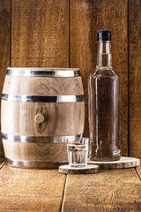 Old oak barrel and glass of high quality distilled alcohol. Brazilian silver cachaça, called pinga, vodka, white rum, liqueur, pure drink, Poitín, sake, brandy or Absinthe.
