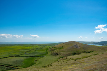 green plain with vegetation and blue sky with clouds