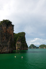 Tourists kayaking in emerald color sea to limestone islands in Phang-nga Bay national park near Phuket Thailand. A famouse activity for summer vacation.
