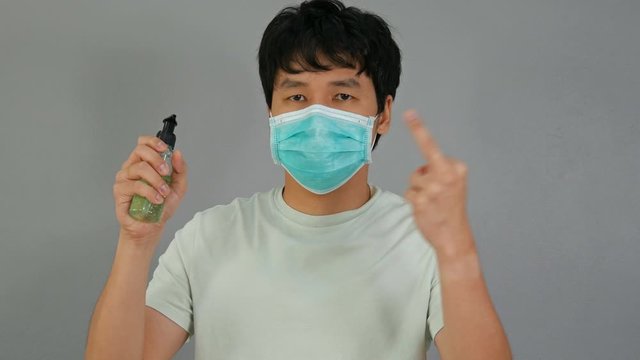 man in a medical mask(surgical mask) holding alcohol gel with middle finger fuck sign hand gesture, coronavirus protection