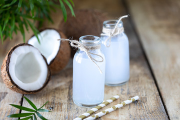 Fresh coconut water in glass bottle on the table. Vegetarian drink. Copy space