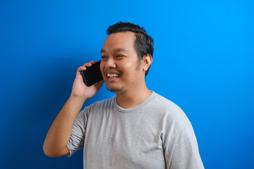 photo of a fat asian man wearing a gray shirt smiling while receiving a phone