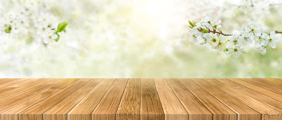 Spring background with white blossoms and sunbeams in front of a wooden table. Spring apple garden on the background