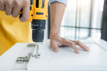 Close up portrait and details of caucasian male worker using electric screwdriver instrument in...
