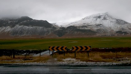 Road sign in a beautiful landscape with snowy mountain and cloudy sky in background - Powered by Adobe