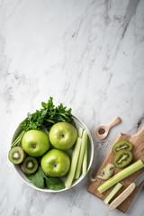 Green fruits and vegetables for making detox smoothie. Apples, kiwi, spinach, celery and parsley on a light background. Top view, place for text.