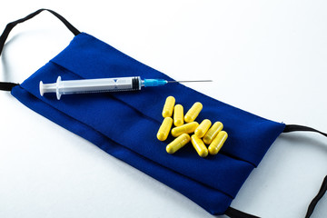 Pills and syringe lie on a blue mask on a white background