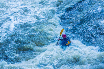 Extreme whitewater rafting trip. A one person in kayak practise traversing the water rapids. Kayaker paddling on the mountain river. Kayaking concept