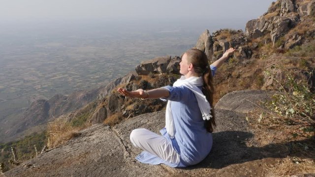 Girl is engaged in meditation yoga on the top of a mountain