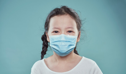 Sad crying asian little girl wearing face protective hygiene mask