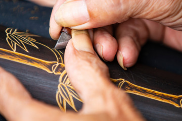 An old man is carving on a bamboo board

