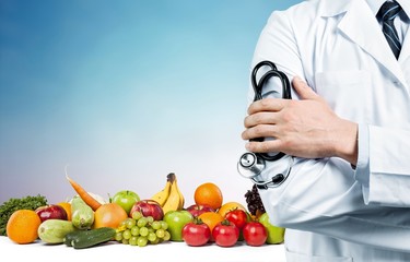 Young man doctor holding stethoscope on vegetables background
