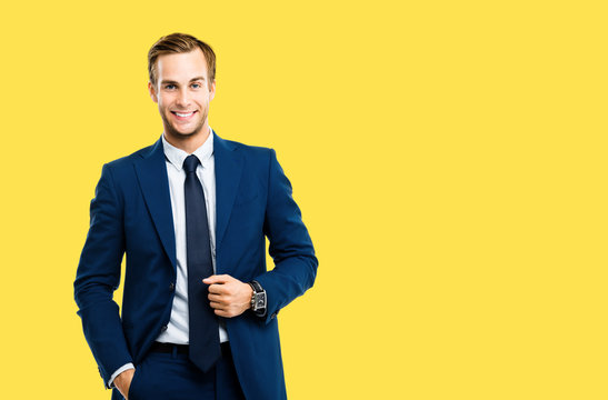 Portrait of happy confident businessman in blue suit and tie, isolated against yellow color background. Business success concept. Smiling man at studio picture. Copy space for some text or slogan.