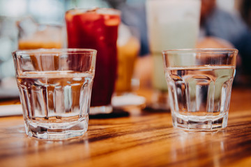 Water bottles and drinking glasses on top of wooden table