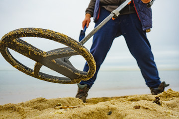 Man with metal detector on sea beach