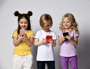 Happy smiling children kids use smartphones texting chatting or make online order shopping broadcast surfing
