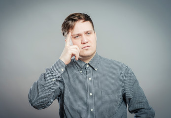 young guy thinks his finger to his temple