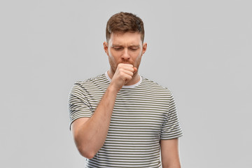 health problem and people concept - unhealthy young man in striped t-shirt coughing over grey...
