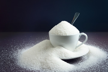 Sugar on a dark background with a spoon. Concept of harm health